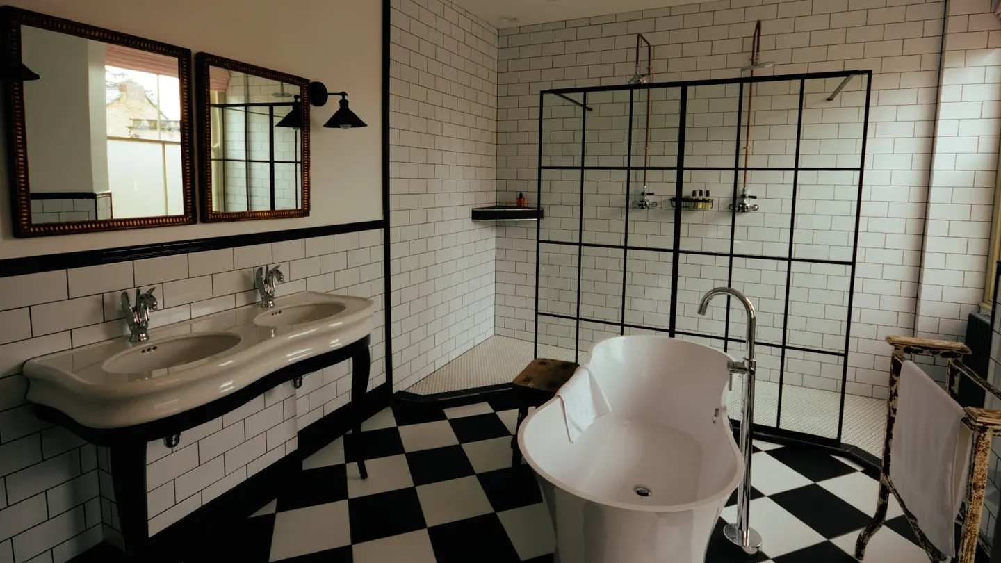 Twin basins, roll-top bath and chequerboard floor in the Feature Bathroom